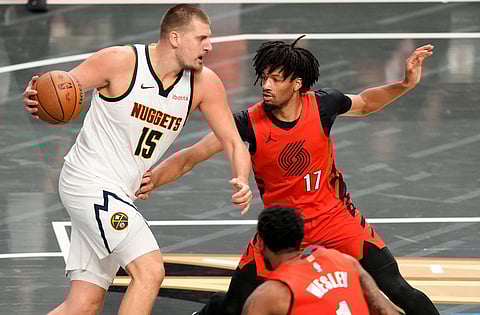 Denver Nuggets center Nikola Jokić (15) tries to get around Portland Trail Blazers guard Shaedon Sharpe (17) during the first half of an NBA Cup basketball game in Portland, Ore.