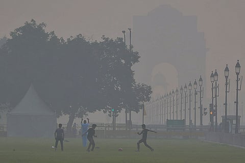 Children play football near India Gate as smog engulfs the area, with the Air Quality Index (AQI) remaining in the 'very poor' category, in New Delhi.