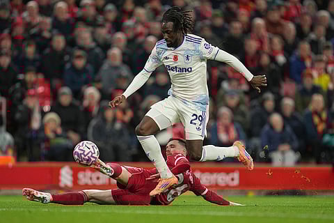 Aston Villa's Evann Guessand challenges for the ball with Liverpool's Andrew Robertson, bottom, during the English Premier League soccer match between Liverpool and Aston Villa in Liverpool, England.