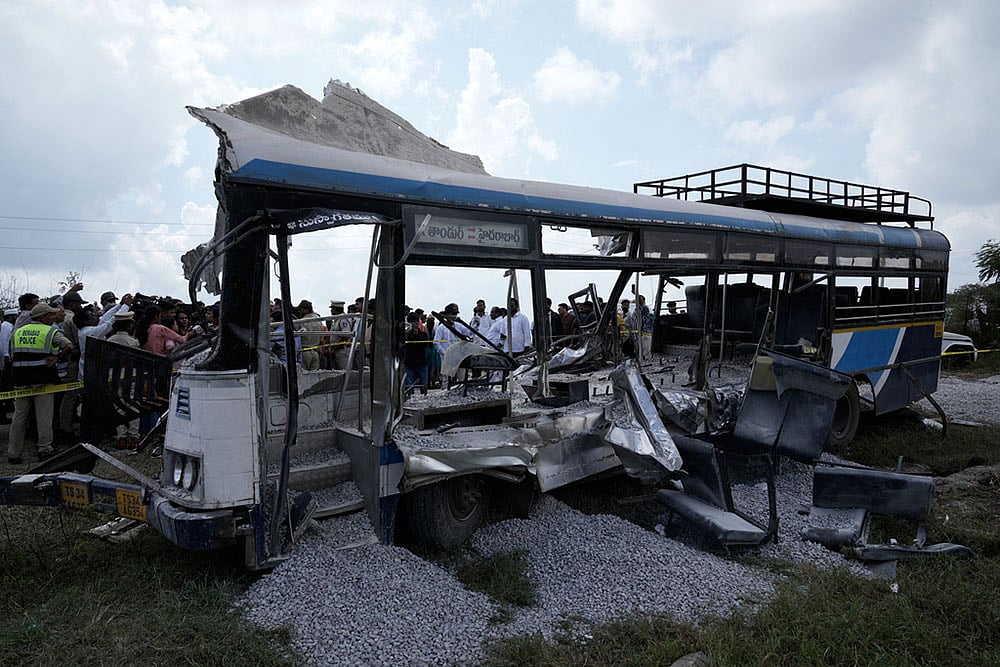 | Photo: AP/Mahesh Kumar A. : People stand next to the passenger bus after a truck loaded with concrete stone chips rammed into it at Chevalla in southern state of Telangana, India.