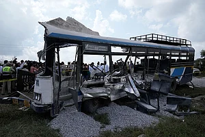| Photo: AP/Mahesh Kumar A. : People stand next to the passenger bus after a truck loaded with concrete stone chips rammed into it at Chevalla in southern state of Telangana, India.