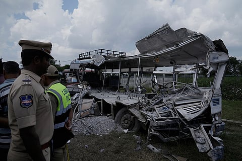 Policemen stand next to the passenger bus after a truck loaded with concrete stone chips rammed into it at Chevalla in southern state of Telangana, India.