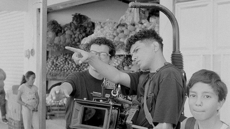 Filmmakers adjusting camera and planning a shot near a fruit market