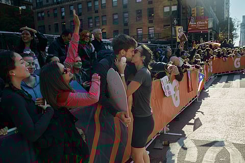 A runner takes a break to kiss her partner during the New York City Marathon in New York.