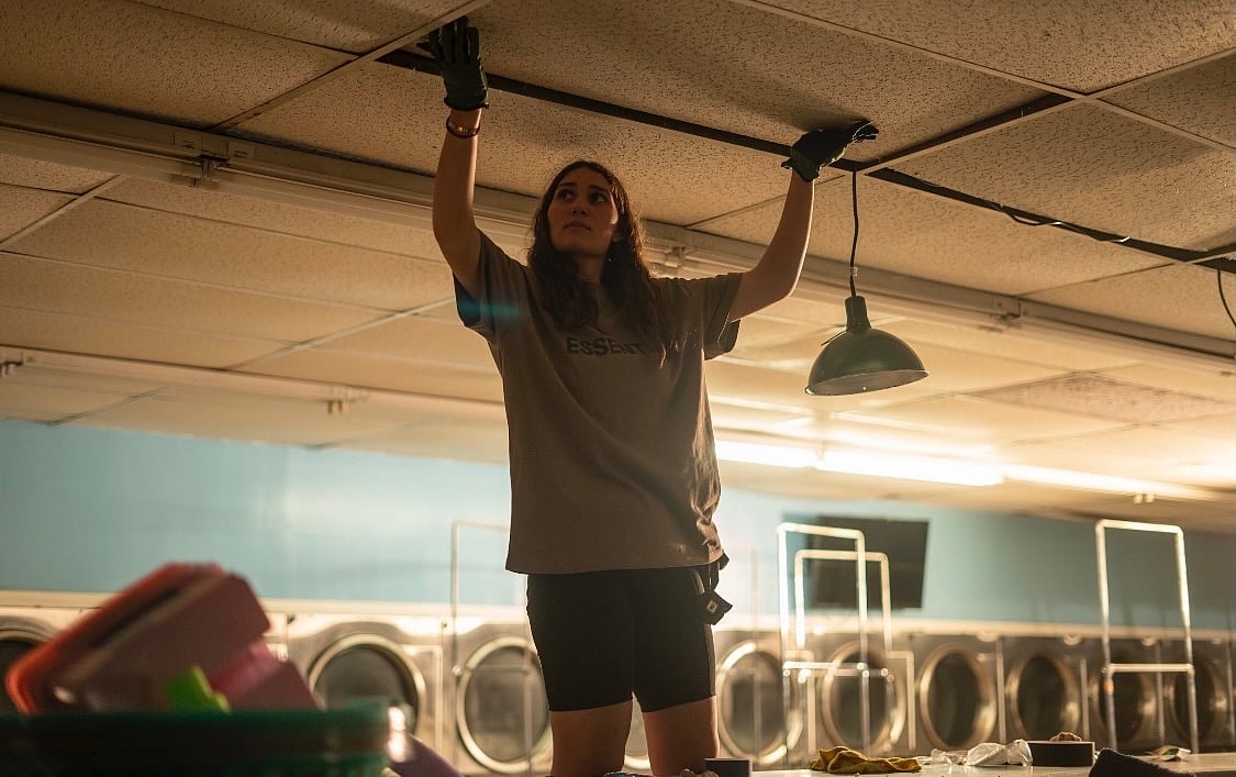 Razan Saylami fixing ceiling tiles in a laundromat.
