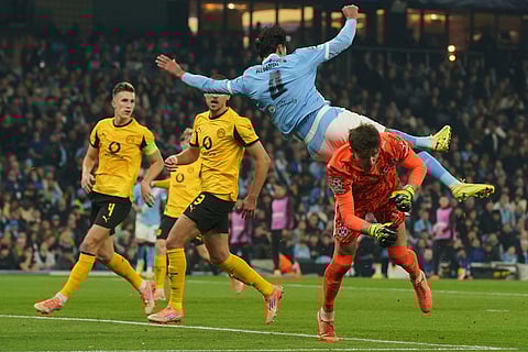 Manchester City's Tijjani Reijnders, top, jumps for the ball besides Dortmund's goalkeeper Gregor Kobel during the Champions League opening phase soccer match between Manchester City and Borussia Dortmund in Manchester, England.