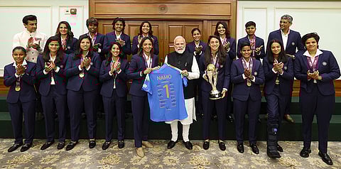 Prime Minister Narendra Modi holds a jersey with captain Harmanpreet Kaur as he poses for a photograph with the Indian women's cricket team, in New Delhi. 