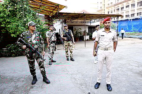 Security personnel stand guard at a polling station during the first phase of Bihar Assembly elections, in Patna.