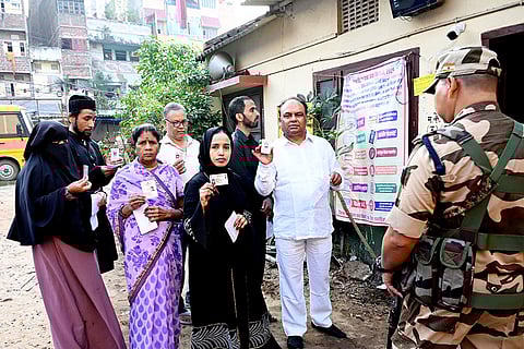People show their identity cards as they arrive to cast votes at a polling station during the first phase of Bihar Assembly elections, in Patna.