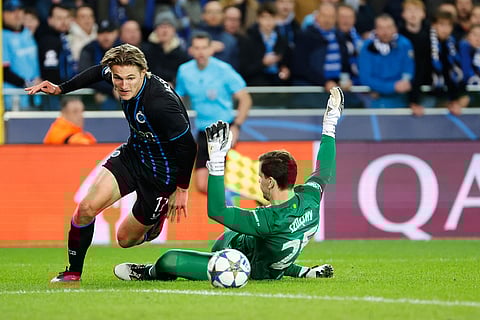 Brugge's Romeo Vermant, left, and Barcelona's goalkeeper Wojciech Szczesny tussle for the ball during the Champions League opening phase soccer match between Club Brugge and Barcelona in Bruges, Belgium.
