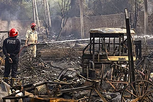 | Photo: PTI : New Delhi: Firemen spray water on charred remains after a fire broke out spreading to around 500 shanties near Rithala metro station, at Rohini area, in New Delhi. Police said several LPG cylinders were said to have exploded late Friday evening, intensifying the blaze and triggering panic among residents.