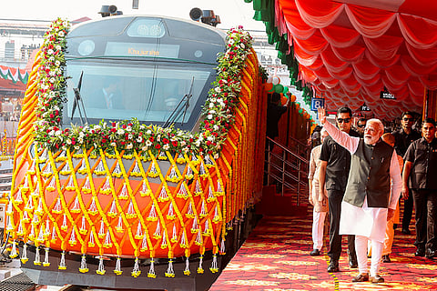In this image, Prime Minister Narendra Modi greets supporters during the flagging off of Vande Bharat Express trains at the railway station, in Varanasi.