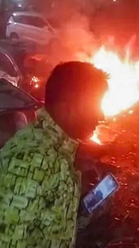 | Photo: PTI : A man rushes away from the spot after a blast occurred in a parked car near Red Fort, leaving multiple vehicles in flames, in New Delhi.