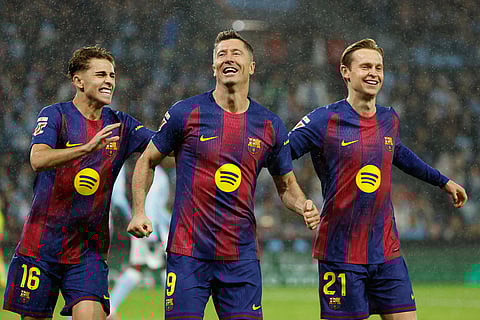 Barcelona's Robert Lewandowski, center, celebrates scoring his side's opening goal from the penalty spot during the Spanish La Liga soccer match between Celta Vigo and Barcelona in Vigo, Spain.