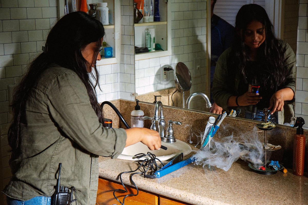 A person working at a cluttered sink with various items