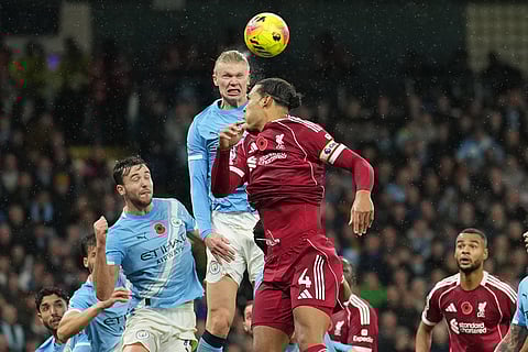 Manchester City's Erling Haaland heads the ball ahead of Liverpool's Virgil van Dijk, centre, during the English Premier League soccer match between Manchester City and Liverpool in Manchester, England.