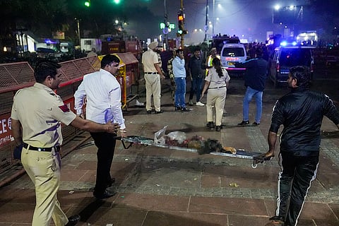 Police personnel carry the mangled remains of a dead person on a stretcher after a blast occurred in a parked car near Red Fort, leaving multiple vehicles in flames, in New Delhi.