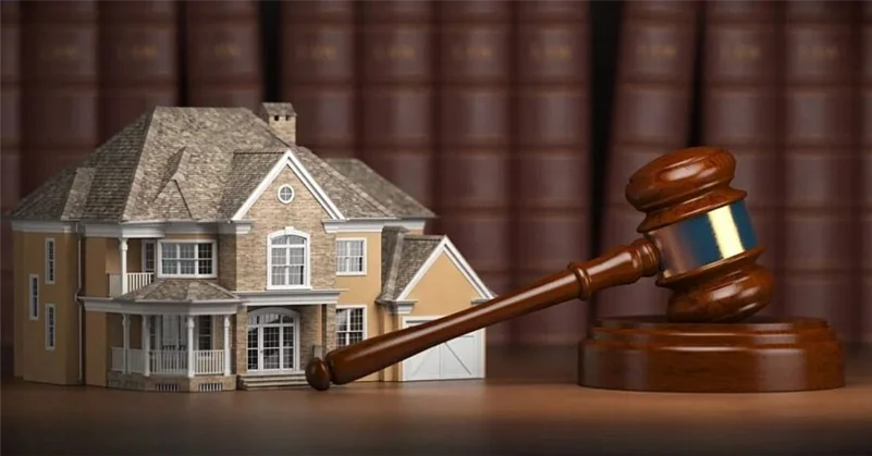 A justice hammer next to a house model