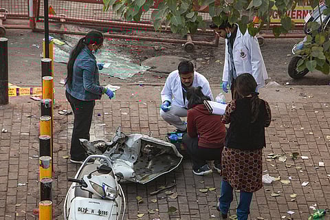 Forensic officials collect samples from the site in the aftermath of the blast that occurred near Red Fort Metro Station on Monday, killing at least nine people and gutting several vehicles, in New Delhi.