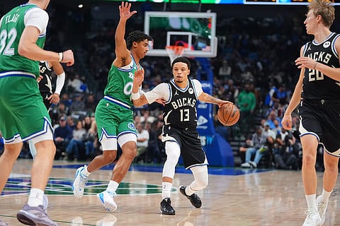 Milwaukee Bucks guard Ryan Rollins (13) dribbles against Dallas Mavericks guard Max Christie during the first half of an NBA basketball game in Dallas.