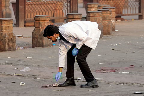 A forensic official collects samples from the site in the aftermath of the blast that occurred near Red Fort Metro Station on Monday, killing at least nine people and gutting several vehicles, in New Delhi.