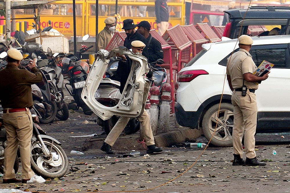 Police personnel at the site in the aftermath of the blast that occurred near Red Fort Metro Station on Monday, killing at least nine people and gutting several vehicles, in New Delhi. - Photo: PTI/Kamal Kishore