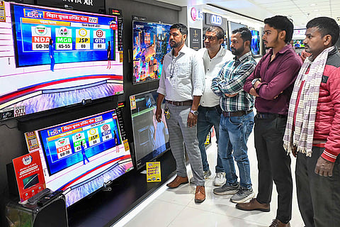 People watch exit poll results on TV sets at a showroom after the second and final phase of the Bihar Assembly elections, in Patna.