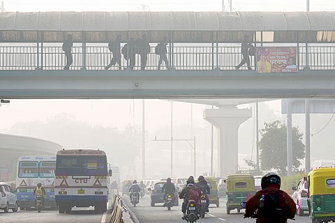 A thick layer of smog shrouds the city road as the Air Quality Index (AQI) remains in the poor category, near ISBT in New Delhi.