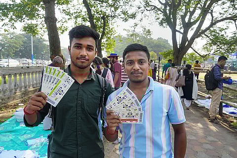 Fans pose with their tickets on the eve of the first Test cricket match of a series between India and South Africa, near Eden Gardens in Kolkata.