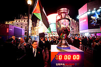 UEFA Unveils Euro 2028 Schedule And Branding Amid Pro-Palestinian Protest In London | Photo: James Manning/Pool via AP : A protester speaking with a police officer near a replica UEFA trophy during the Euro 2028 launch at Below The Lights, Piccadilly Circus, London.