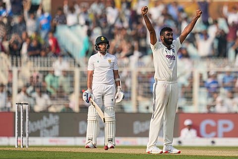 India's Jasprit Bumrah, right, celebrates a five-wicket haul after taking the wicket of South Africa's Keshav Maharaj, left, on the first day of the first cricket test match between India and South Africa in Kolkata.