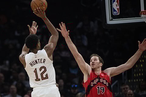 Cleveland Cavaliers' De'Andre Hunter (12) shoots over Toronto Raptors' Jakob Poeltl (19) during the first half of an NBA basketball game in Cleveland.