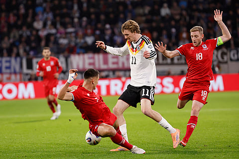 Germany's Nick Woltemade, center, fights for the ball with Luxembourg's Laurent Jans, right, during the 2026 World Cup group A qualifying soccer match between Luxembourg and Germany in Luxembourg.