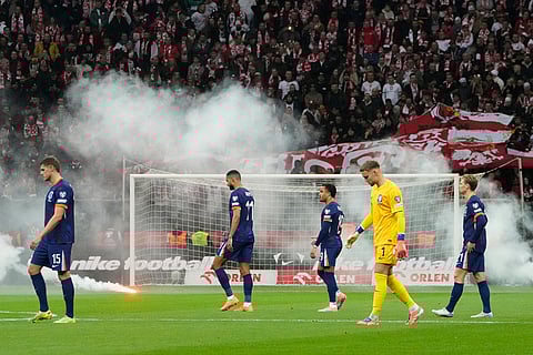 The Netherlands players walk on the pitch while the game is interrupted after flares were thrown from the stands on to the pitch during a World Cup 2026 group G qualifying soccer match between Poland and the Netherlands in Warsaw.