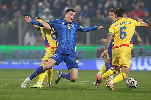 Romania's Vlad Dragomir, left, and Marius Marin, right, challenge for the ball with Bosina's Benjamin Tahirovic during the 2026 World Cup Group H qualifier soccer match between Bosnia and Romania in Zenica, Bosnia and Herzegovina.