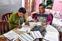| Photo: PTI : A Booth Level Officer (BLO) assists a voter in filling out the enumeration form for the special intensive revision (SIR) of electoral rolls, in Bikaner, Rajasthan.