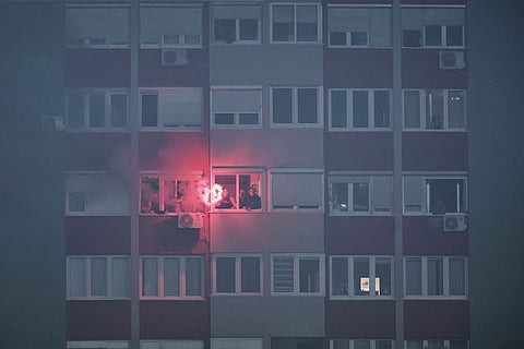 Bosnia's supporters lit a flare as they watch the game from the apartment building outside the stadium during the 2026 World Cup Group H qualifier soccer match between Bosnia and Romania in Zenica, Bosnia and Herzegovina.