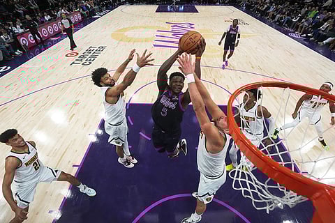 Minnesota Timberwolves guard Anthony Edwards (5) shoots as Denver Nuggets guard Jamal Murray, left, and Nikola Jokic, right, defend during the second half of an NBA basketball game, in Minneapolis. 