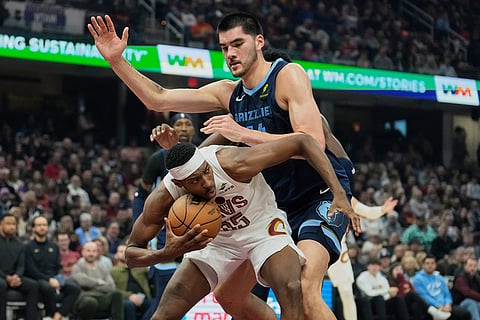 Cleveland Cavaliers forward Nae'Qwan Tomlin, bottom, is fouled by Memphis Grizzlies center Zach Edey, top, in the first half of an NBA basketball game in Cleveland. 