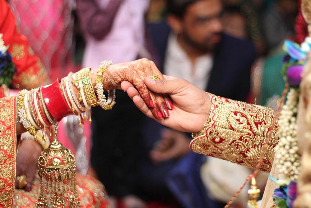 Close-up of a bride and grooms hands touching during an Indian wedding ceremony.