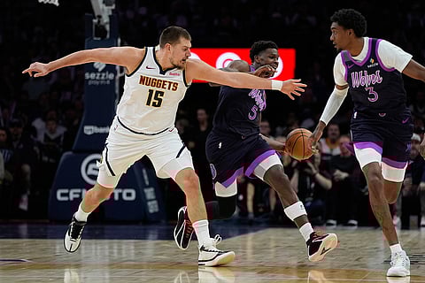 Minnesota Timberwolves guard Anthony Edwards (5) is fouled by Denver Nuggets center Nikola Jokic (15) during the first half of an NBA basketball game in Minneapolis.