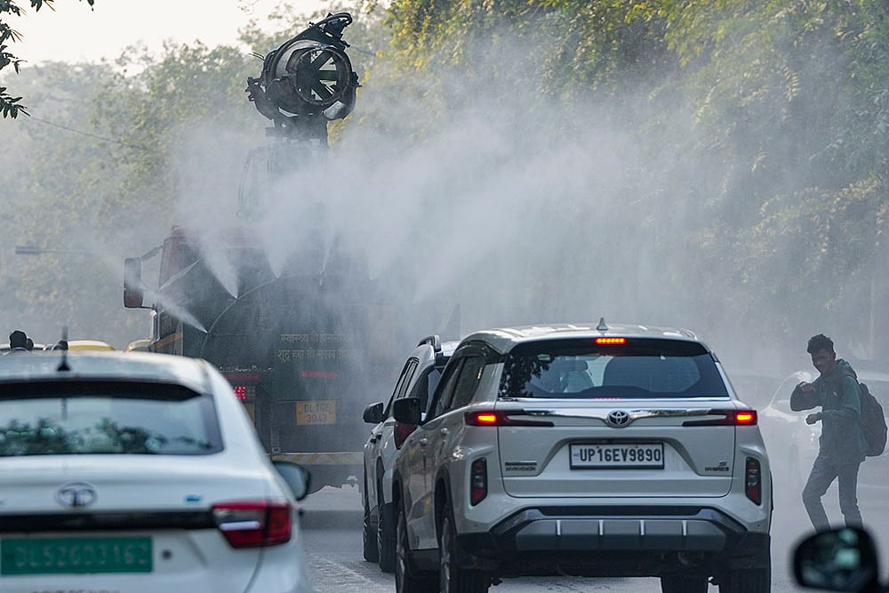 An 'anti-smog' vehicle sprays water mist to settle down particulate matter as other vehicles ply the road, amid poor air quality, in New Delhi. - Photo: PTI/Atul Yadav