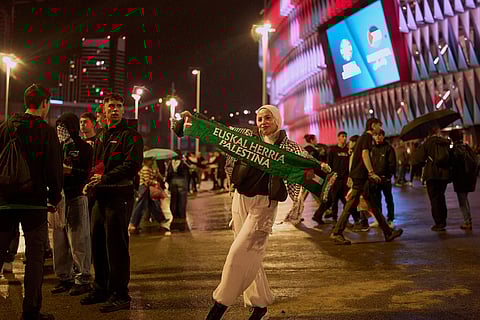 A woman holds a scarf with Palestinian symbols ahead of a friendly match between a selection of Palestinian players and a group of Spanish players from the Basque Country, held to protest Israel's military actions in Gaza, in Bilbao, Spain.