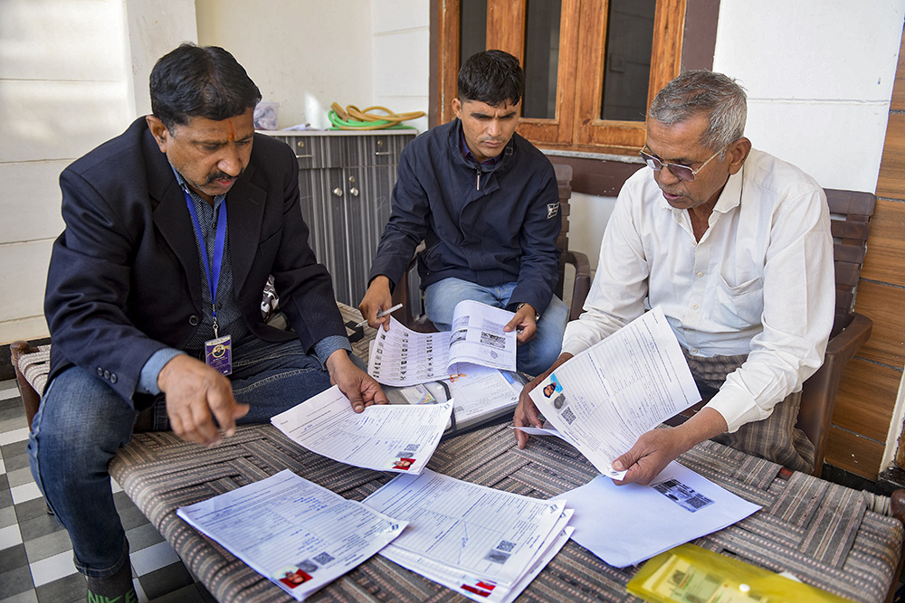 Booth Level Officers (BLOs) assist a voter in filling out the enumeration form for the special intensive revision (SIR) of electoral rolls, in Bikaner, Rajasthan.