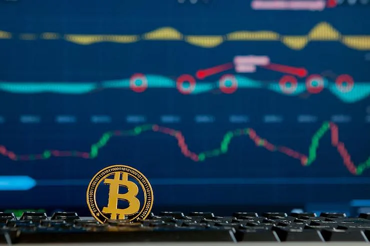 Gold Bitcoin coin on keyboard with stock charts