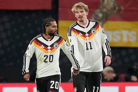 Germany's Serge Gnabry, left, and Nick Woltemade shake hands after scoring during a group A World Cup qualifiying soccer match between Germany and Slovakia in Leipzig, Germany.
