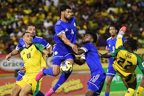 Curacao's Roshon Van Eijma, in the air, fights for the ball with Jamaica's Gregory Leigh, right, and Jonathan Russell during a World Cup 2026 qualifying soccer match in Kingston, Jamaica.