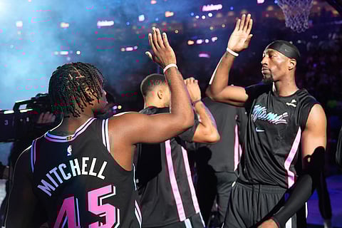 Miami Heat center Bam Adebayo, right, greets guard Davion Mitchell (45) before an NBA basketball game against the Golden State Warriors in Miami. 