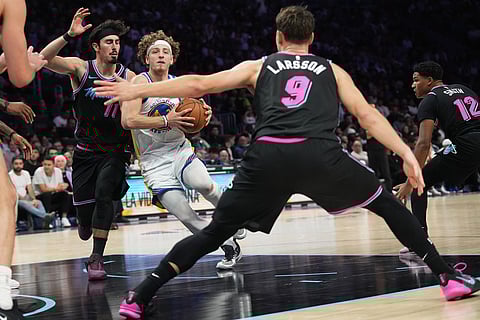 Golden State Warriors guard Brandin Podziemski, center drives to the basket as Miami Heat forward Jaime Jaquez Jr. (11) and guard Pelle Larsson (9) defend during the second half of an NBA basketball game in Miami. 