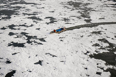 Workers spray defoaming chemical in the Yamuna River to reduce the toxic foam, at Kalindi Kunj, in New Delhi.